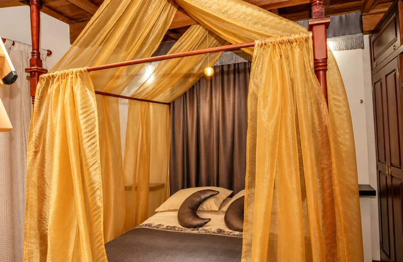 Dormitorio de Suite Luna con velos dorados sobre la cama