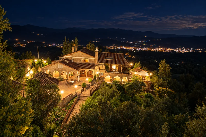 Villa Manantial de Sueños iluminada al anochecer, con las luces del valle al fondo